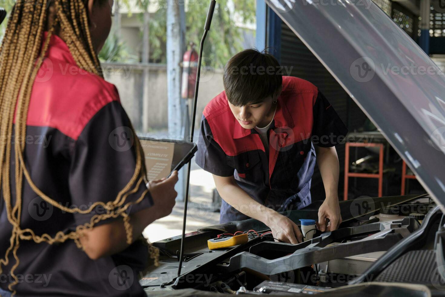 Two professional automotive mechanical partners check and repair an EV car battery and hybrid engine at a maintenance garage, expert electric vehicle service, and fixing occupations auto industry. photo