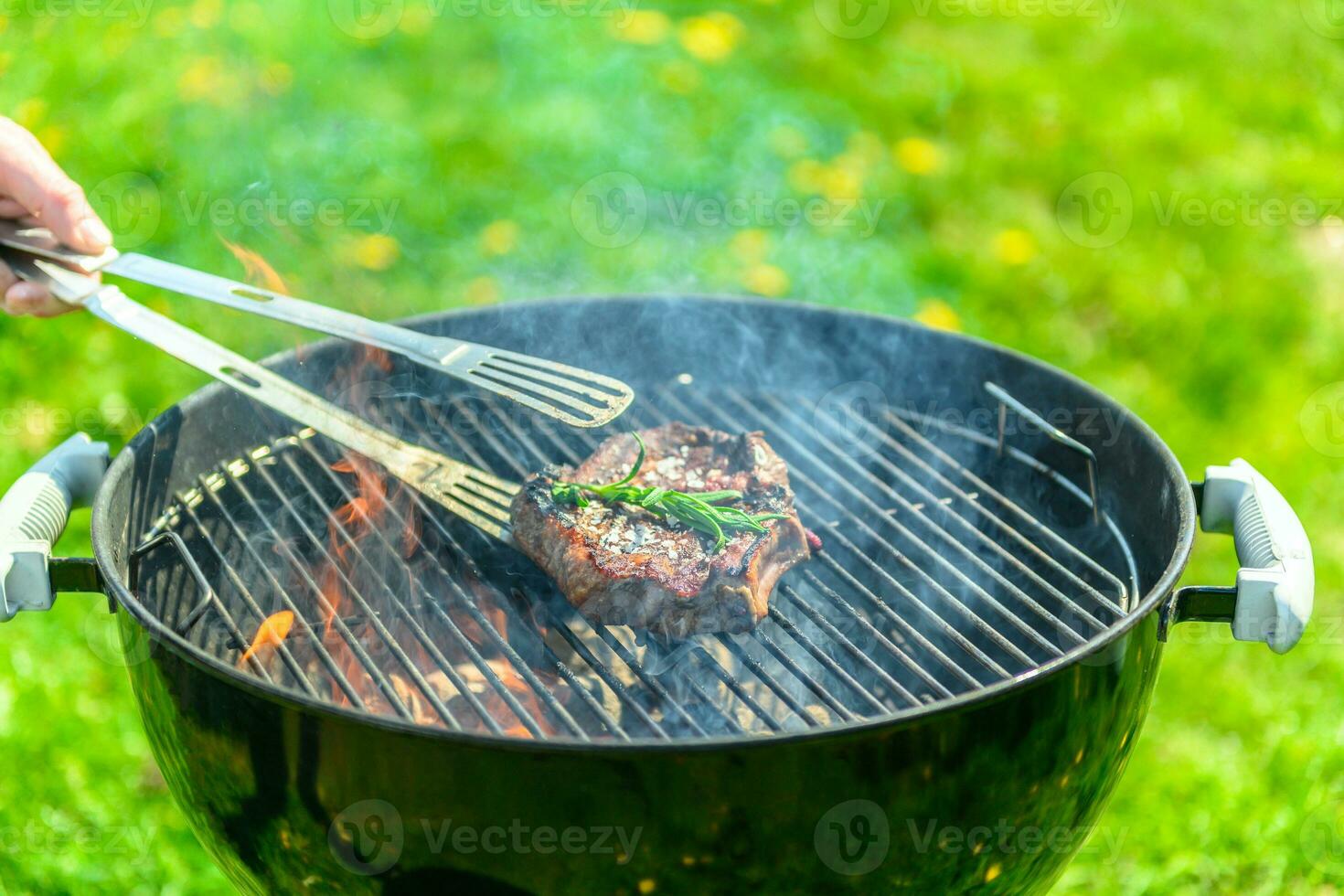 Delicious steak sizzling on a BBQ with a lot of fire and smoke photo
