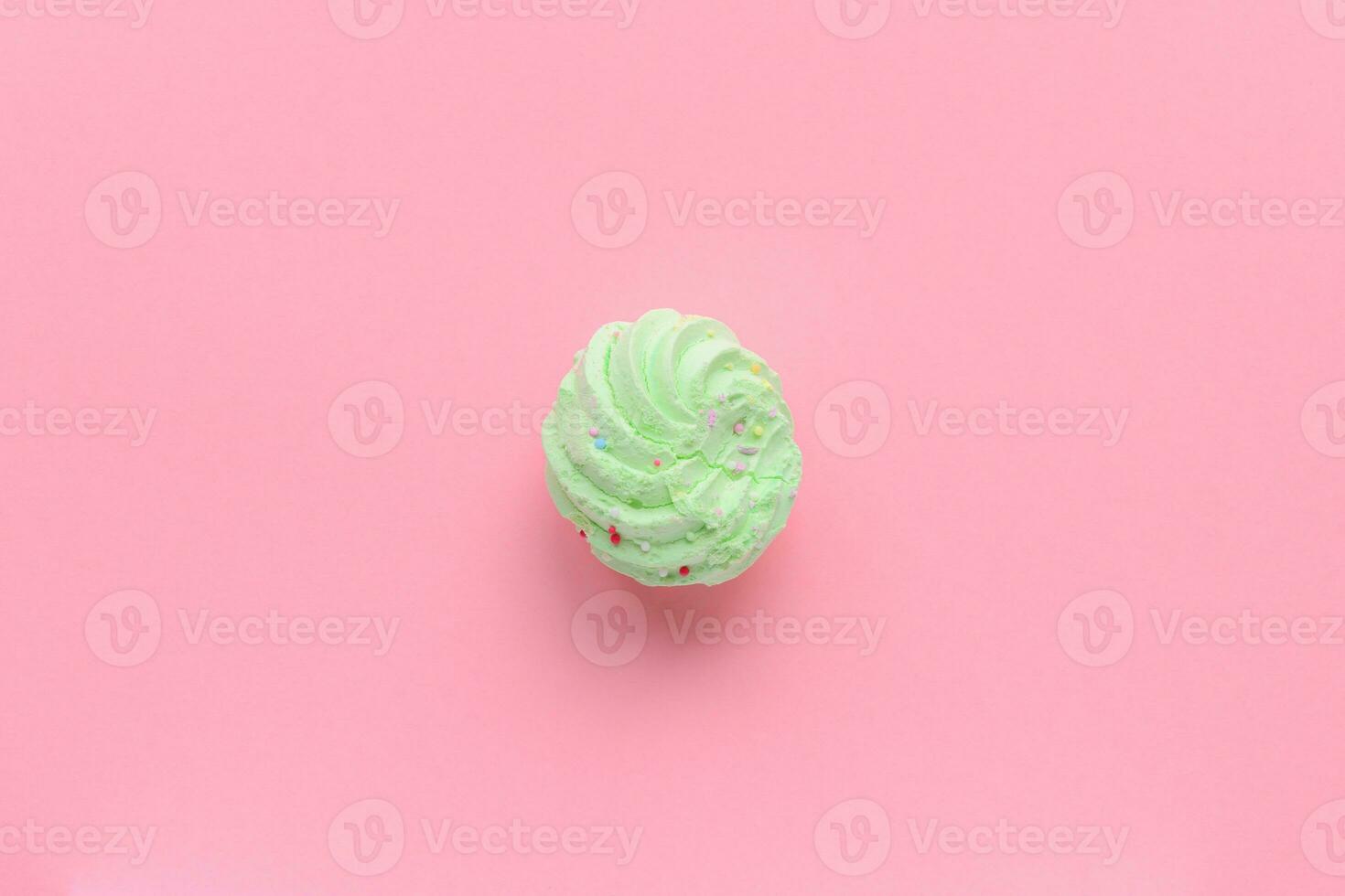 Single delicious green meringues on pink background copy space photo