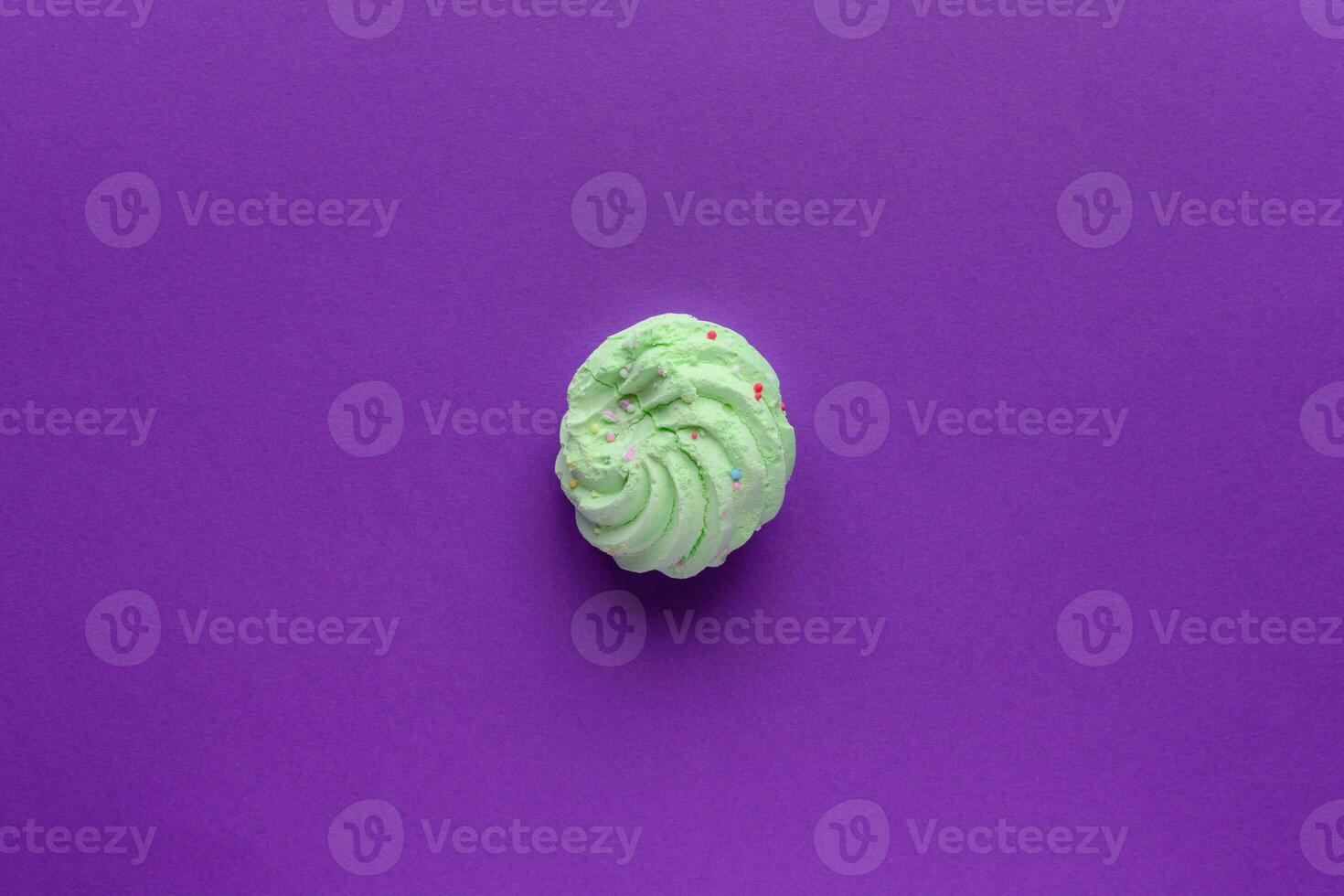 Single delicious green meringues on purple background copy space photo