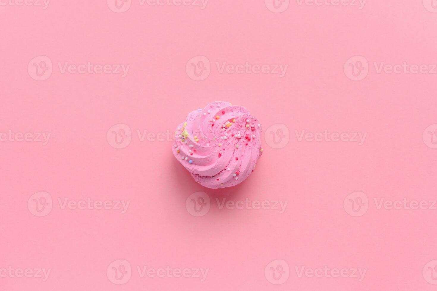 Single delicious pink meringues on pink background copy space photo