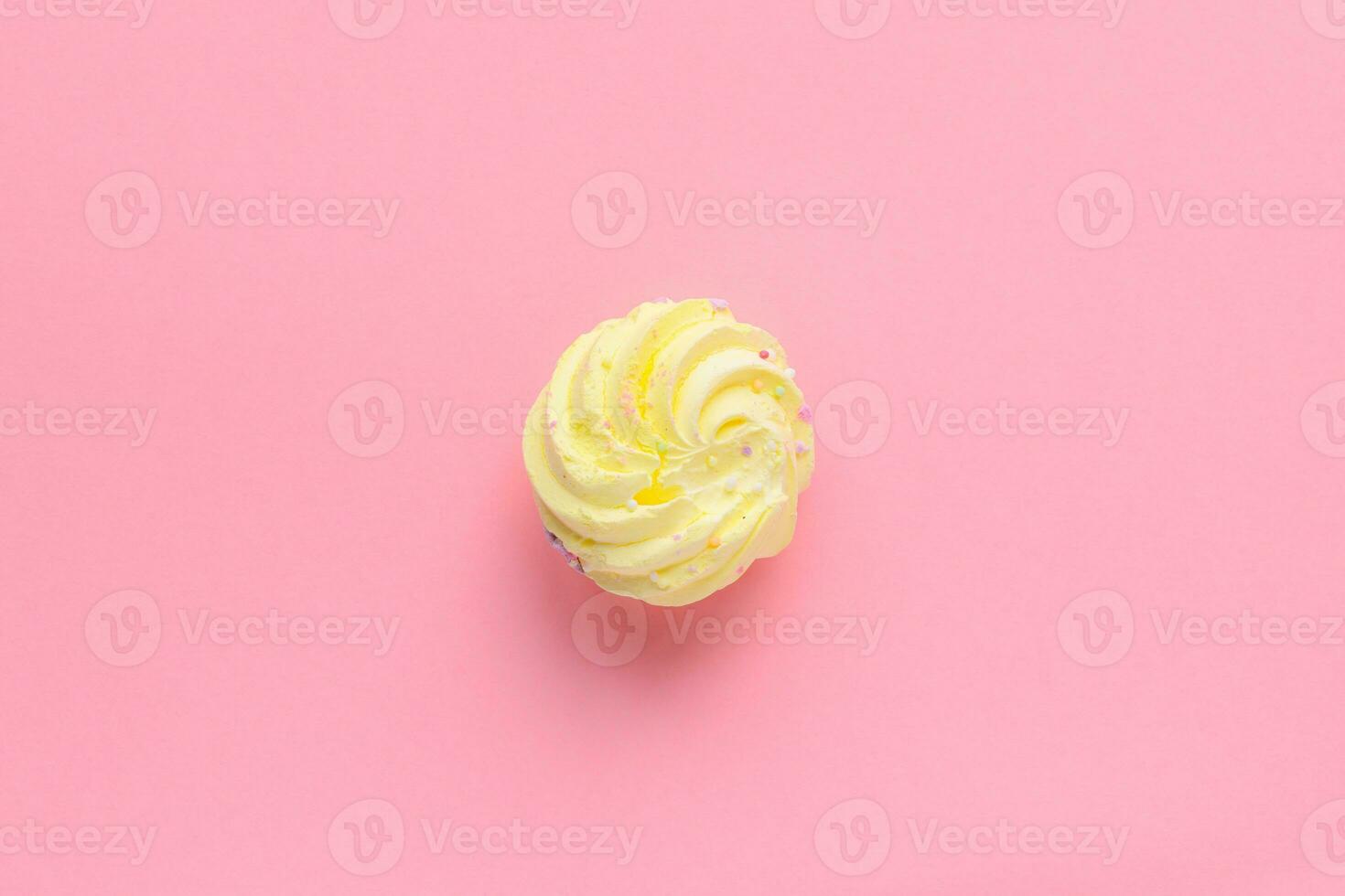 Single delicious yellow meringues on pink background copy space photo
