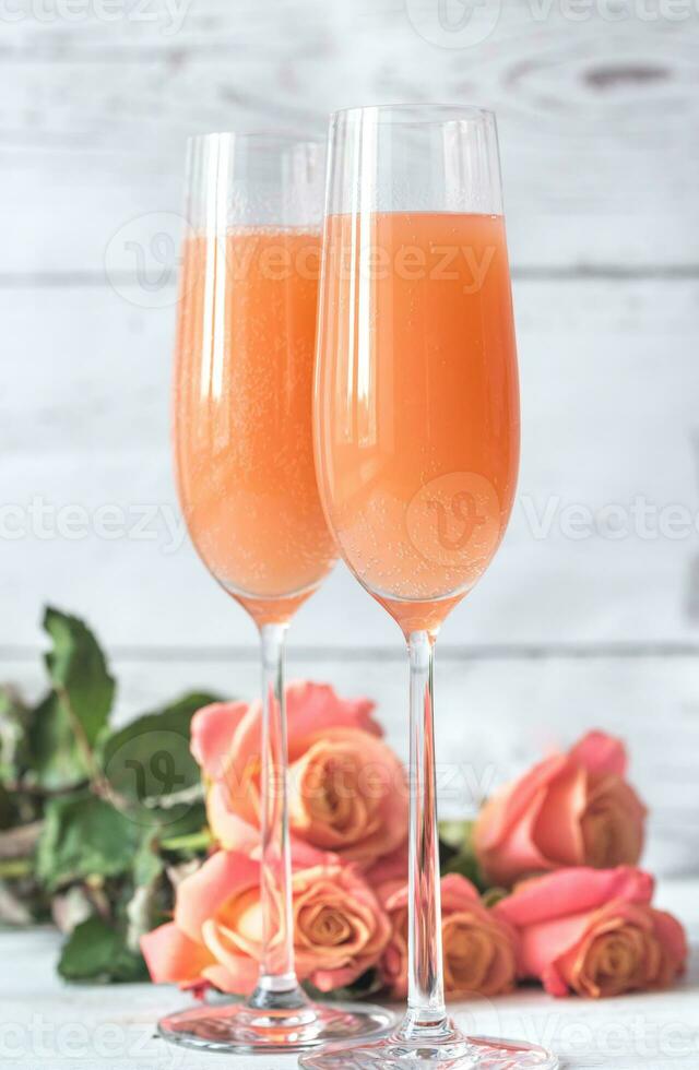 Two glasses of bellini cocktail with bouquet of roses photo