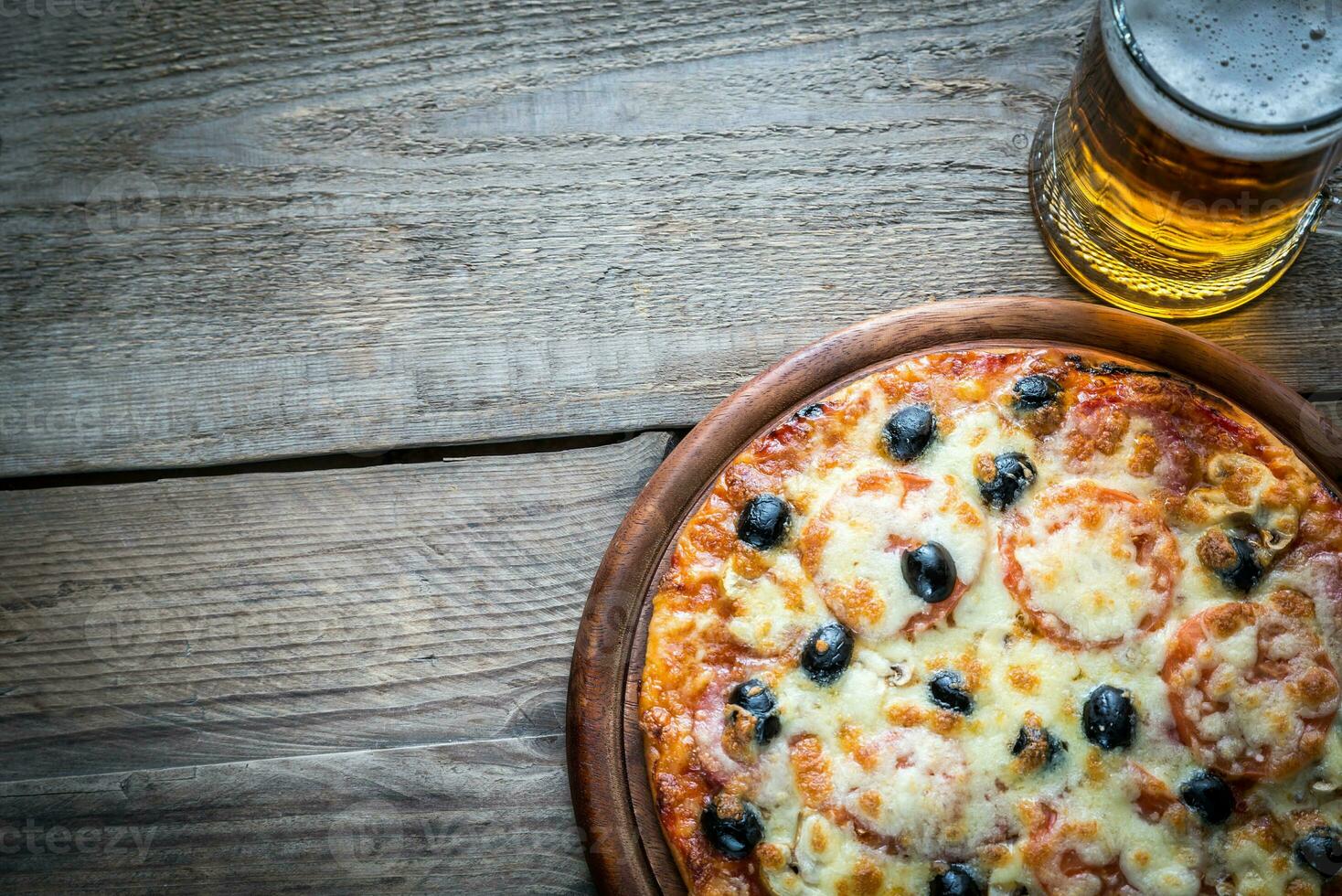 cocido Pizza con un vaso de cerveza foto