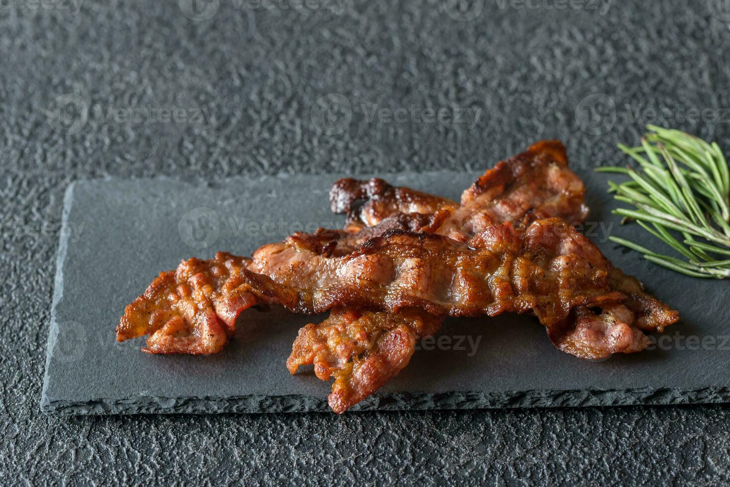 Fried bacon strips on the stone dark board photo