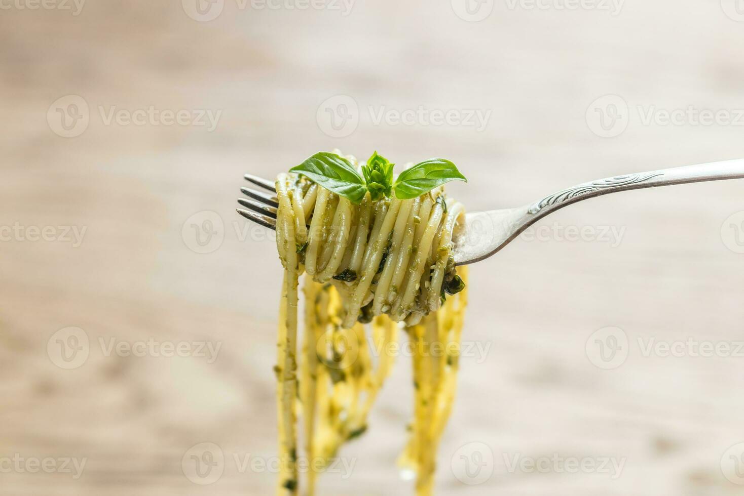 espaguetis con salsa pesto y hojas de albahaca en el tenedor foto