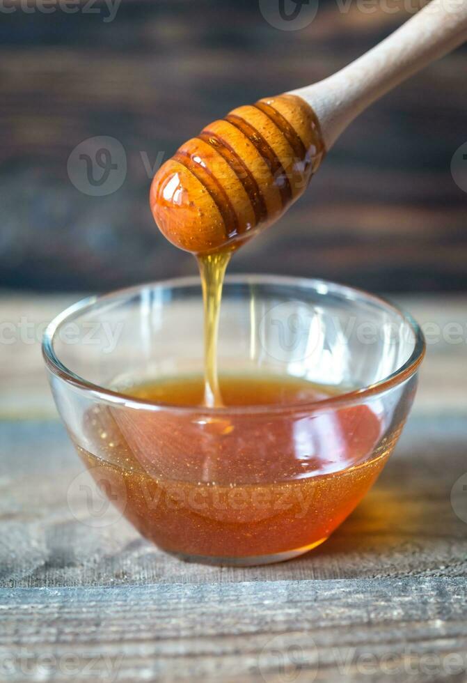 Bowl of honey on the dark wooden background photo