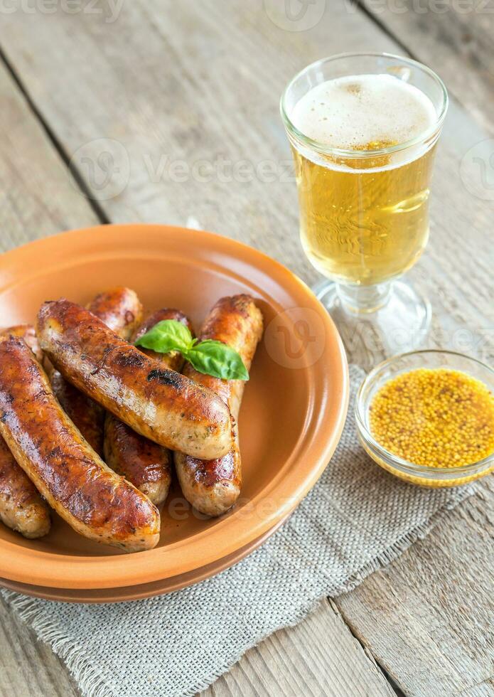 salchichas a la parrilla con un vaso de cerveza foto