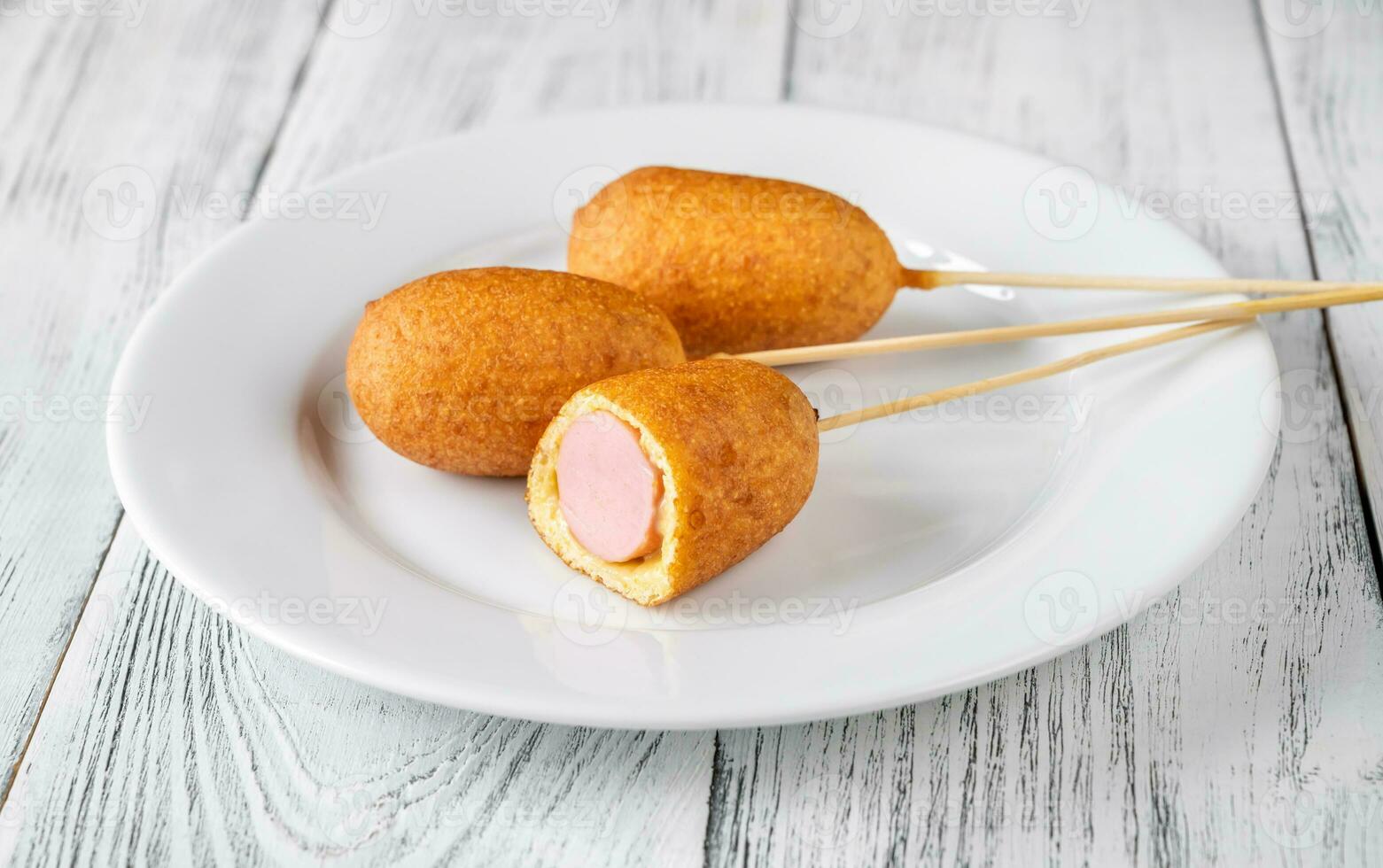 Corn dogs on white serving plate photo