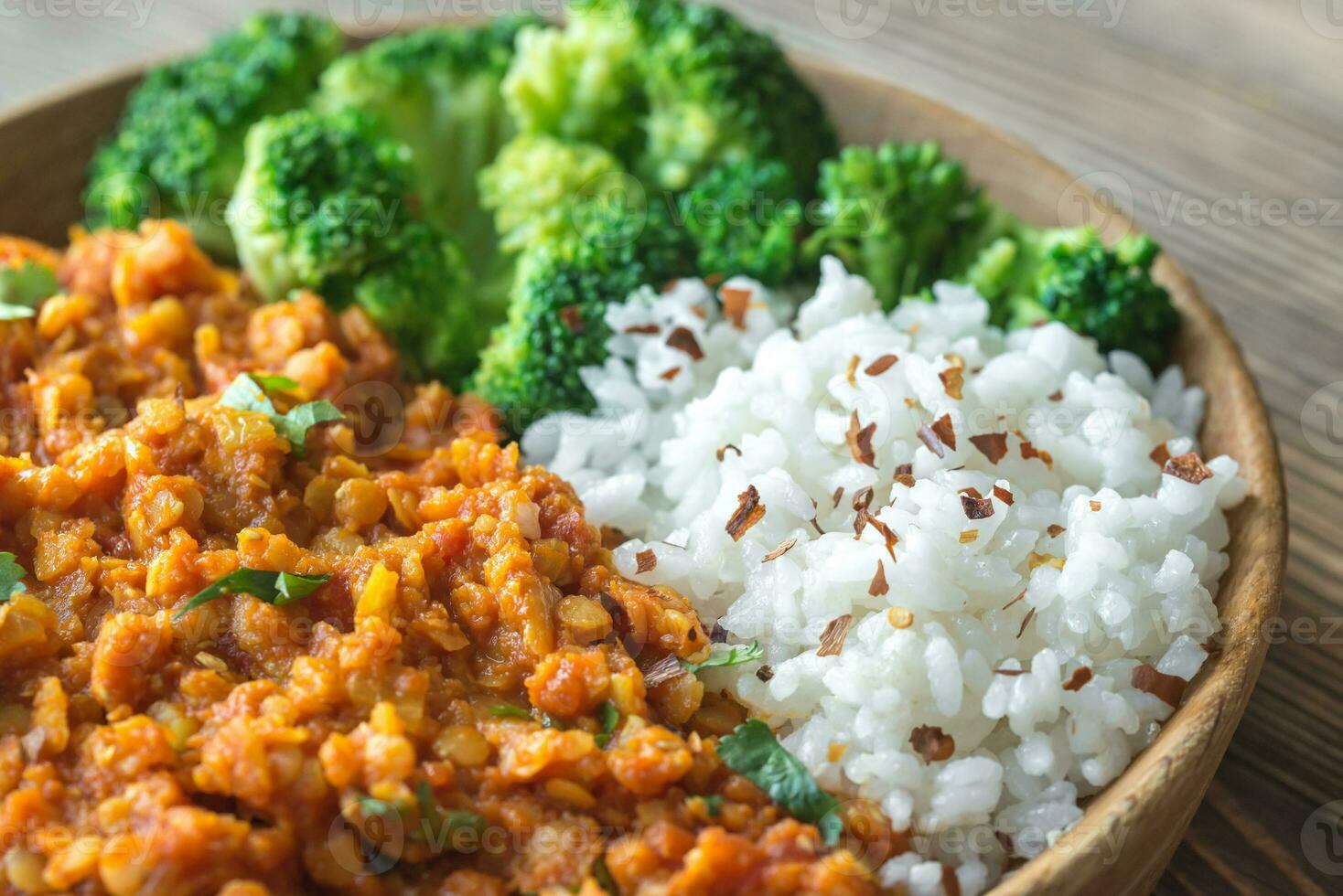 Bowl of red lentil curry with white rice and broccoli photo