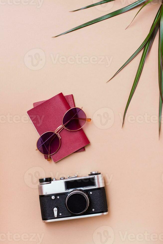 Bright travel flat lay with sunglasses, passports and a vintage camera on a beige background. Car travel. Vertical view. Copy space photo