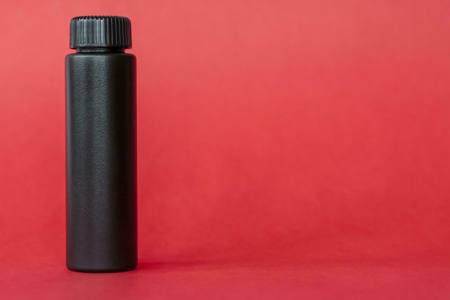Black bottle with cream on a red background. Skin care, Moisturizing and nourishing or sunscreen. photo