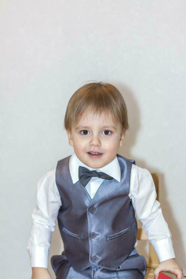 A little boy holds and hands over a red box, a Valentine's Day theme concept. Portrait of a cute boy in a suit with a bow tie. photo