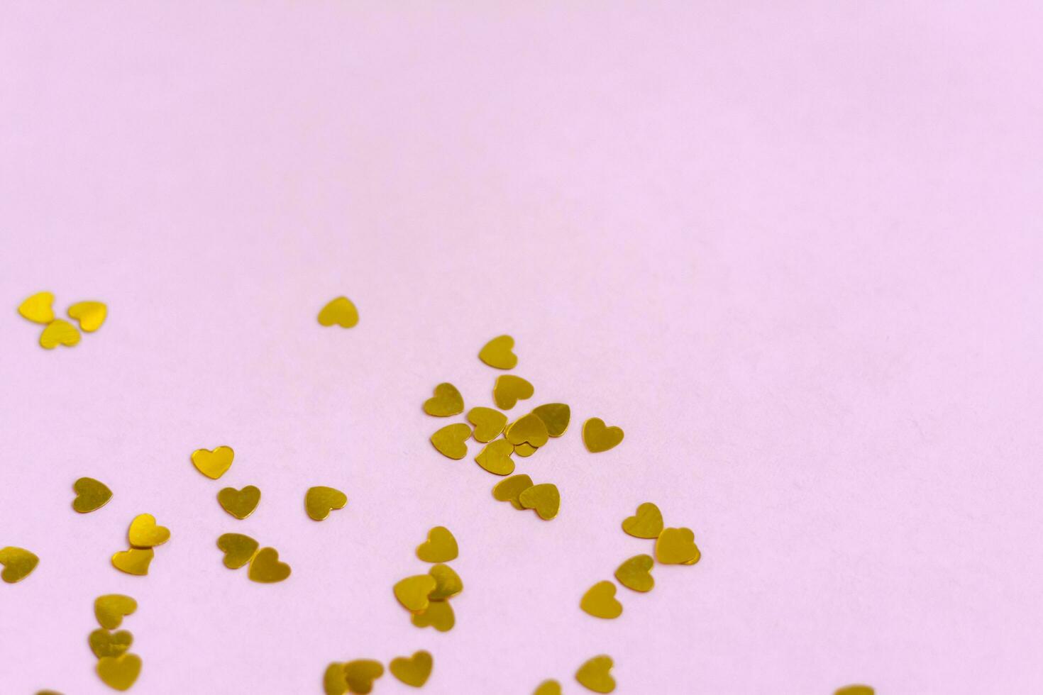 Pink background with gold hearts, sequins. The concept of the Valentine's Day theme. Postcard, template, background photo