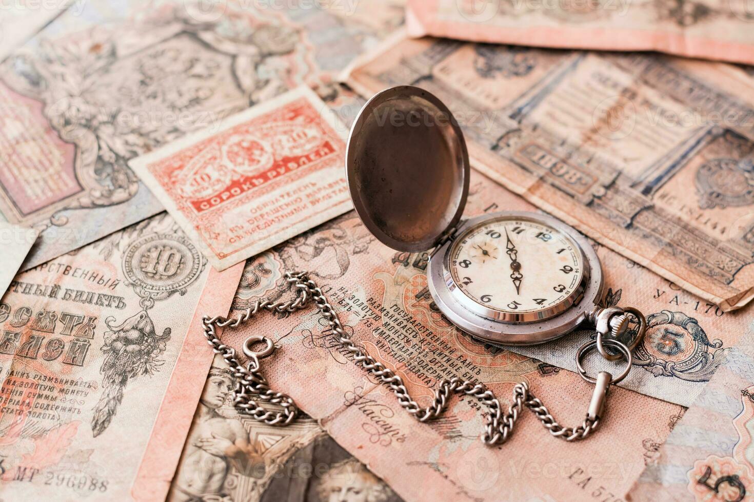 Antique watches on a chain lie on old ruble banknotes out of circulation on a brown background. photo