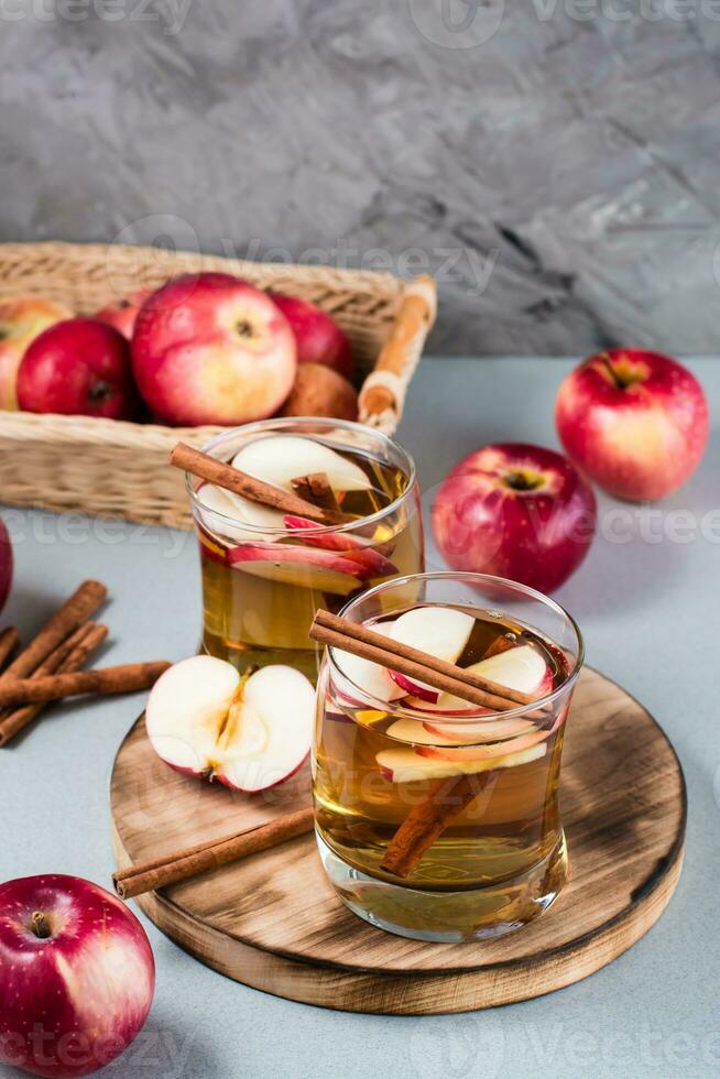 Homemade apple cider with cinnamon in glasses on a gray background. Warming winter drinks. Vertical view photo