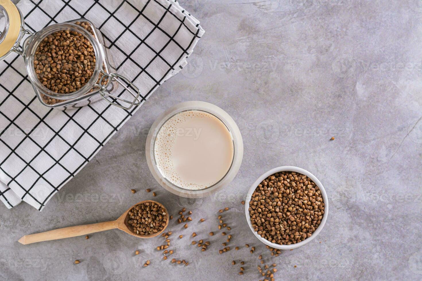 Vegan dairy-free buckwheat milk in a glass and cereals in a bowl on the table top view photo