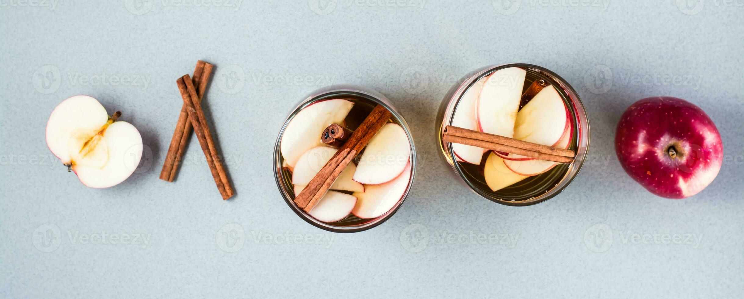Homemade apple cider with cinnamon in glasses on a gray background. Warming winter drinks. Top view. Web banner photo