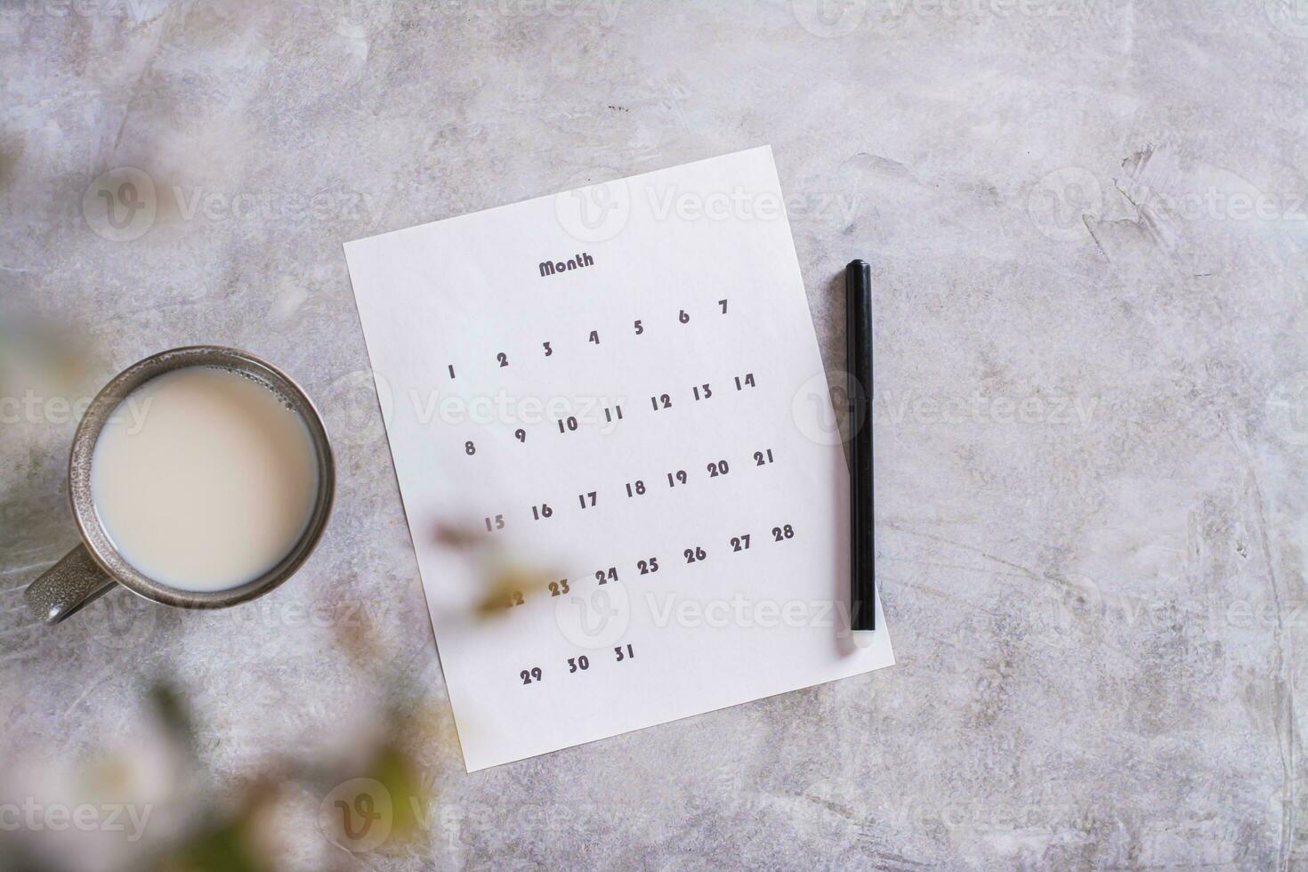 Calendar sheet for planning and a cup of coffee with milk on the table top view photo