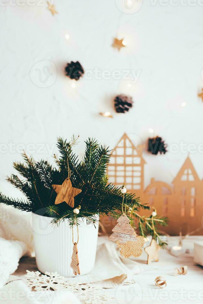 Organization of a festive Christmas table. Fir bouquet in a vase decorated with wooden ornaments on the Christmas table. Eco-friendly and homemade lifestyle. Vertical view photo