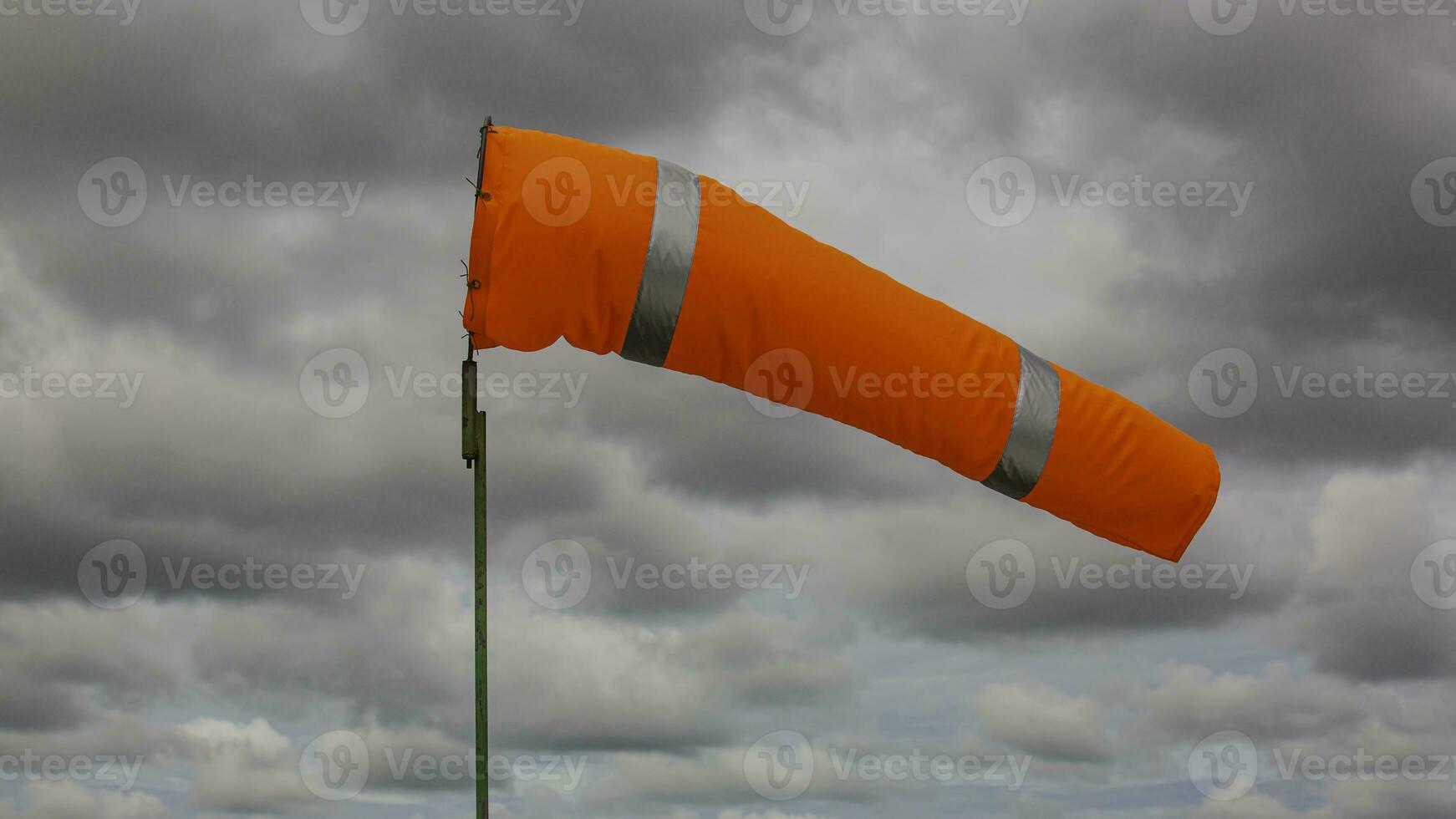 Windsock indicator of wind on tank chemical cone indicating wind direction and force. Horizontally flying windsock wind vane with cloud sky photo