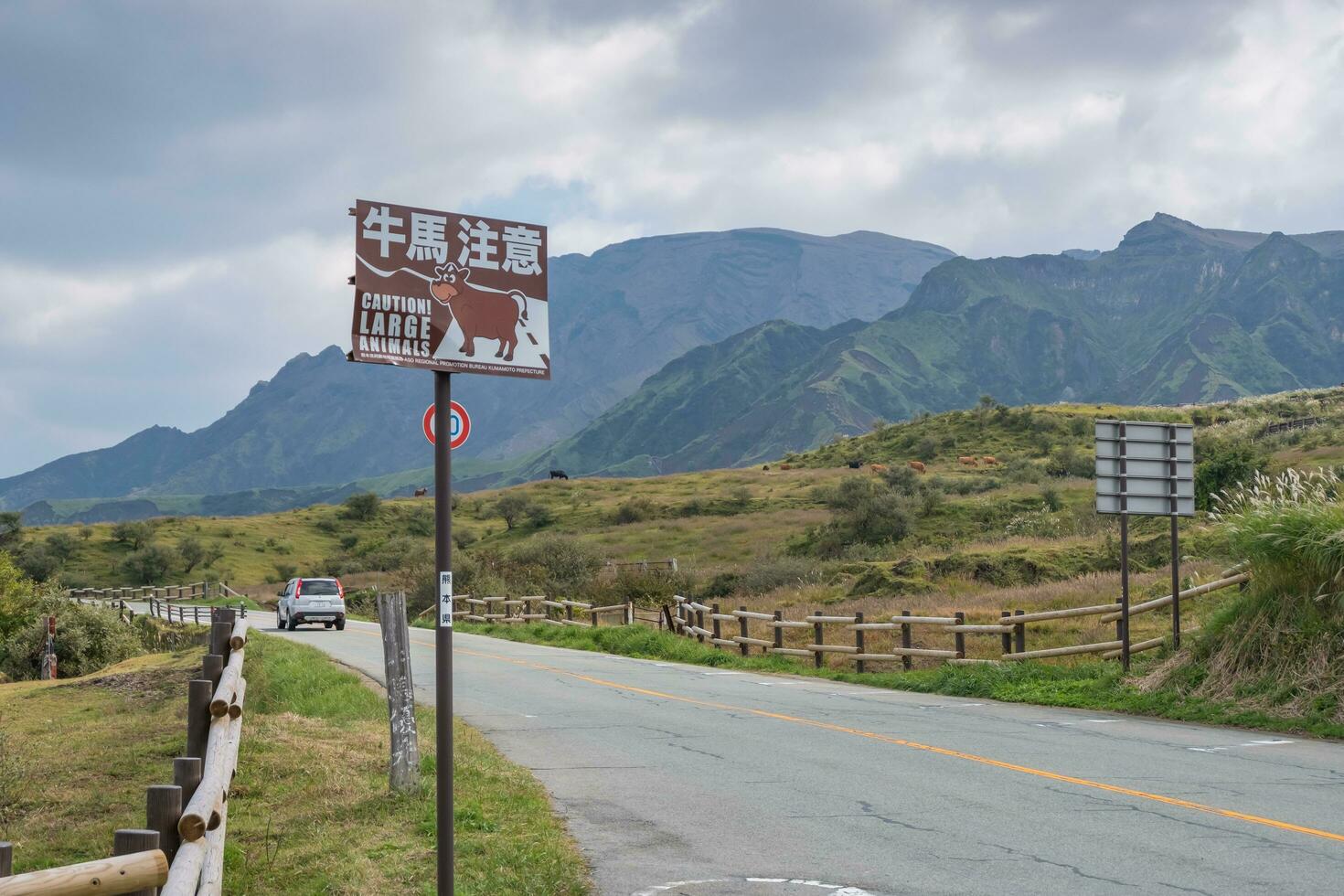 Aso,Kumamoto,Kyushu,Japan - October 17, 2018  Green grass field with Aso mountain background and roadway photo