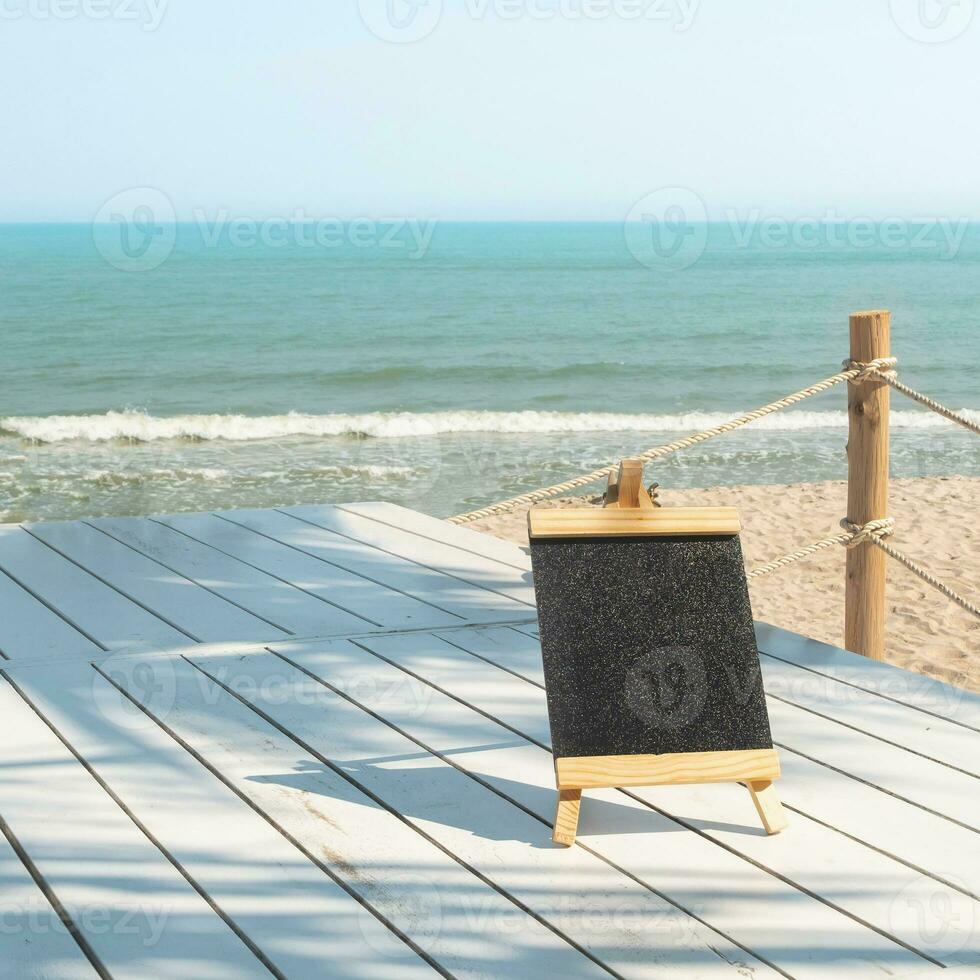 Chalk board with wooden frame with sand beach background photo