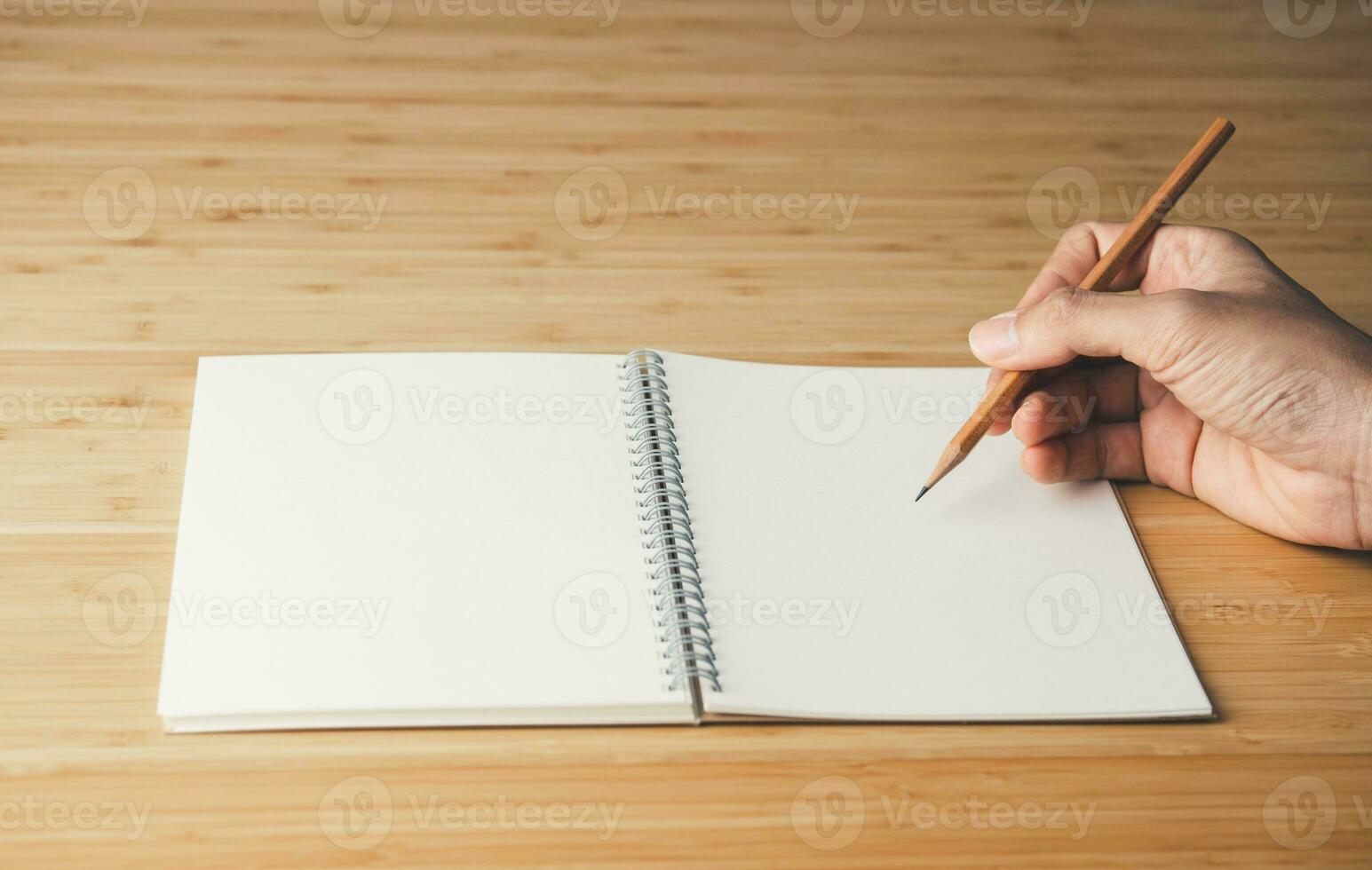 Notebook on the wooden table and hand holding the pencil. Education, Learning and Idea concept photo