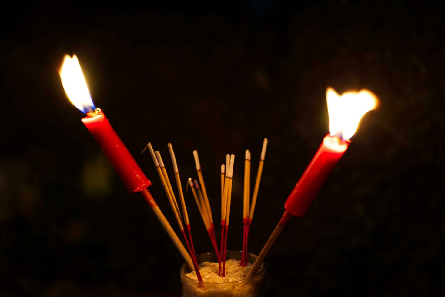 burning Incense and red candles to pay homage on a dark background