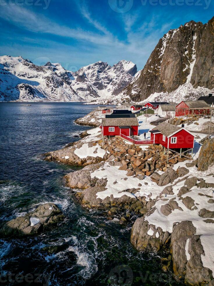 Red fishing cabins in Lofoten Norway by drone, rorbuer snow mountain photo