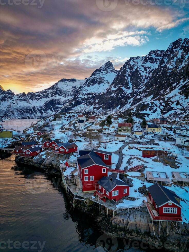 Red fishing cabins in Lofoten Norway in sunset by drone, Snow mountains photo