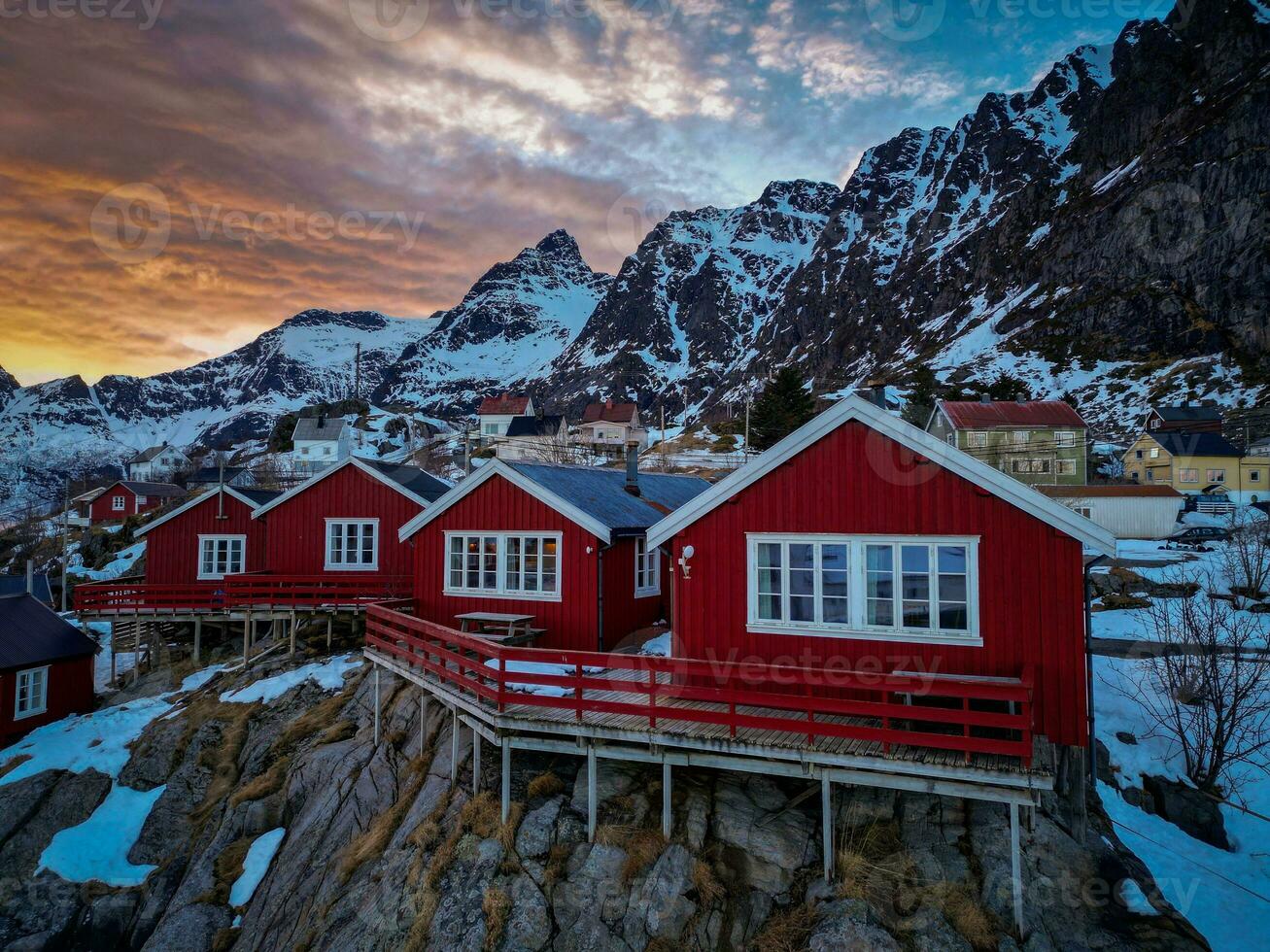 Red fishing cabins in Lofoten Norway in sunset by drone, Snow mountains photo
