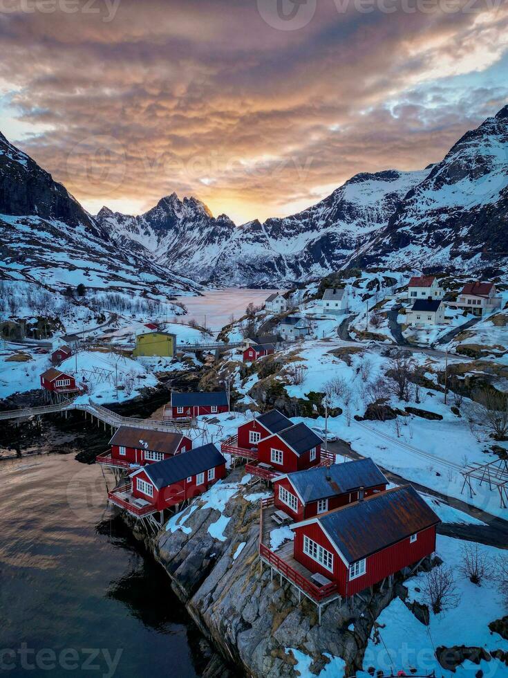 Red fishing cabins in Lofoten Norway in sunset by drone, Snow mountains photo