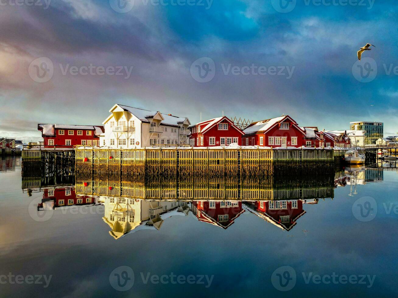 Red fishing cabins in lofoten Norway reflecting in the water in sunrise by drone photo