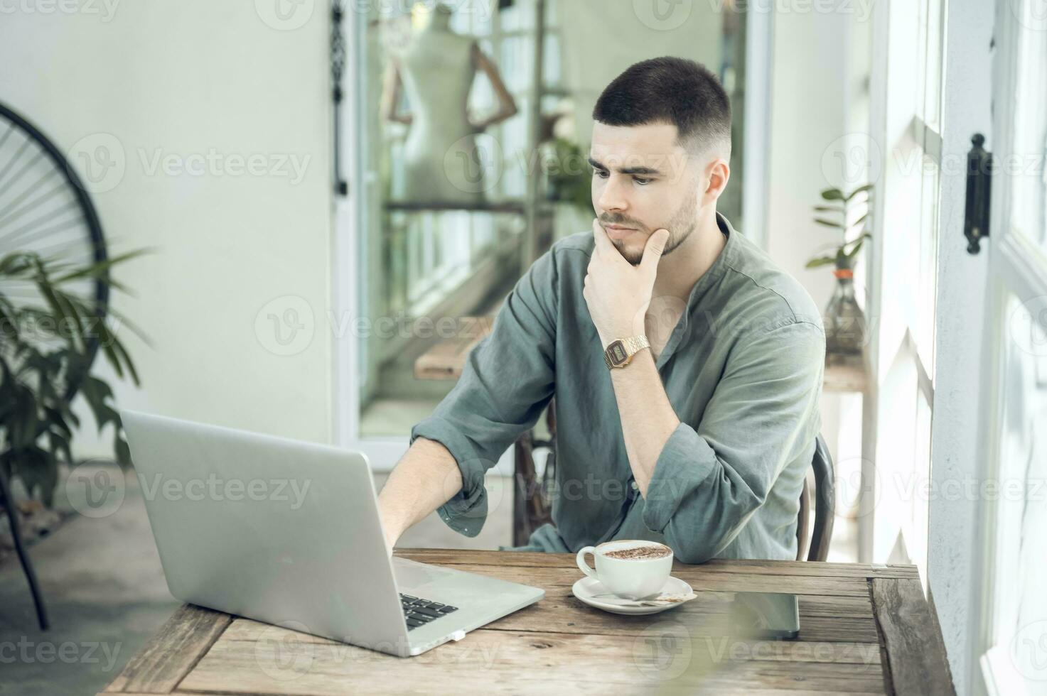 handsome young businessman Working on laptop and working online while sitting at coffee shop table, businessman working outdoors side view photo