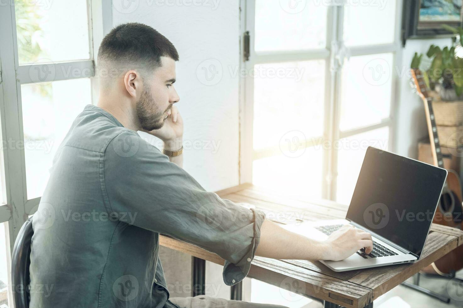 handsome young businessman Working on laptop and working online while sitting at coffee shop table, businessman working outdoors side view photo