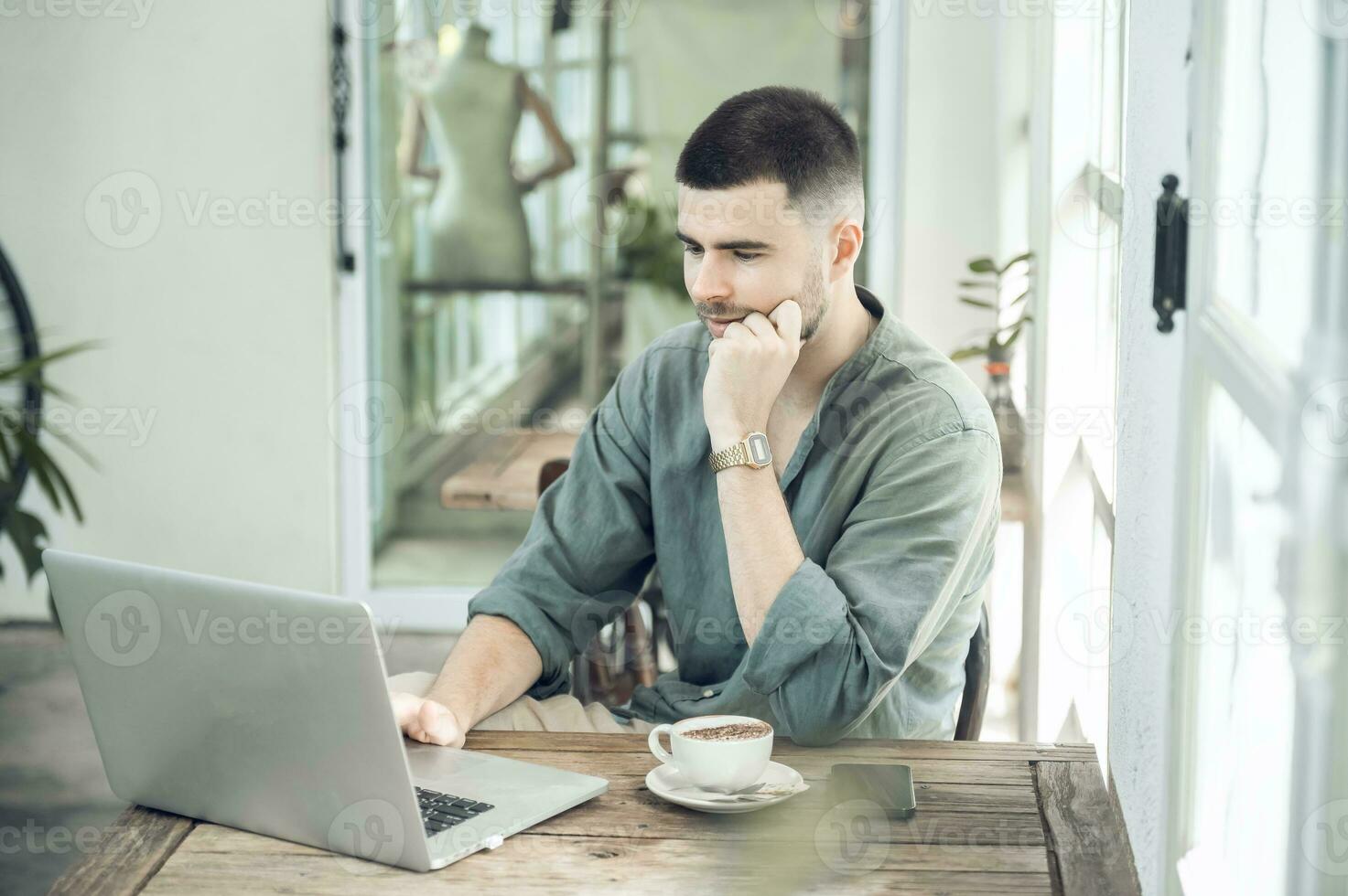 handsome young businessman Working on laptop and working online while sitting at coffee shop table, businessman working outdoors side view photo