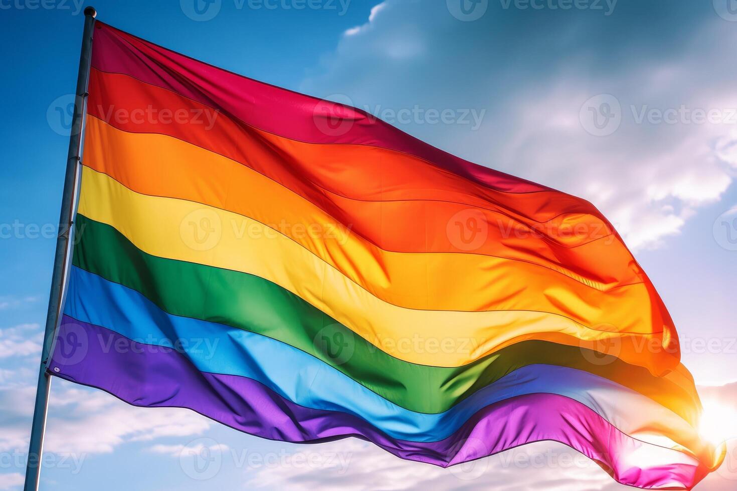 Happy Pride day rainbow lgbt gay flag being waved in the breeze against a cloudy sky, photo