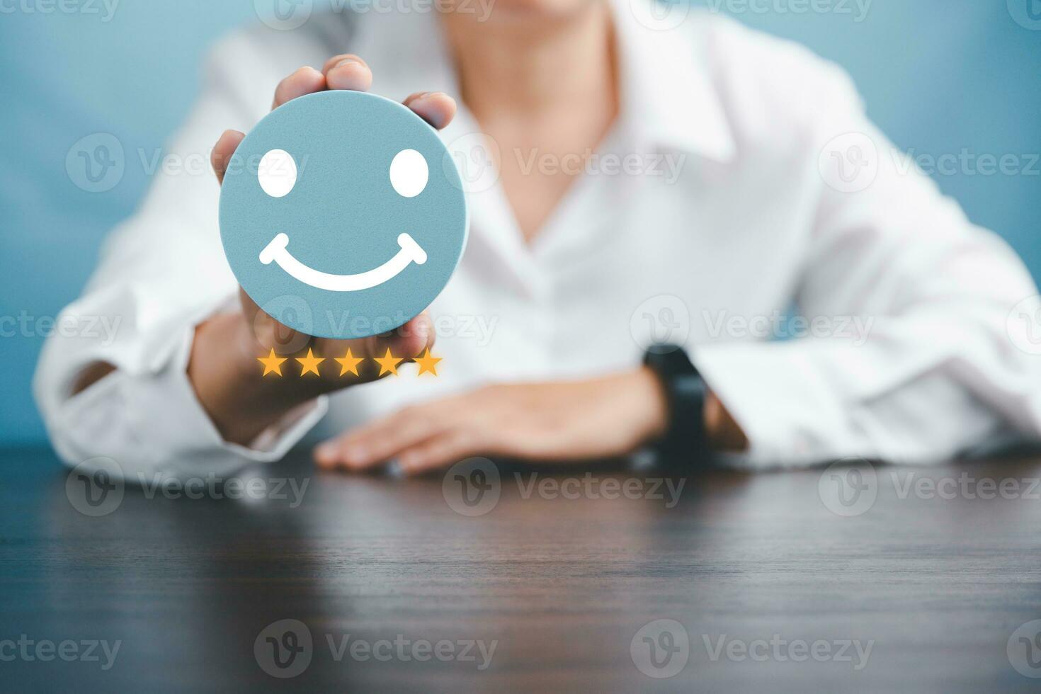 Woman hand holding happy face smile face icon on round blue object. Customer experience and service with satisfaction concept. positive thinking, mental health assessment, world mental health day. photo