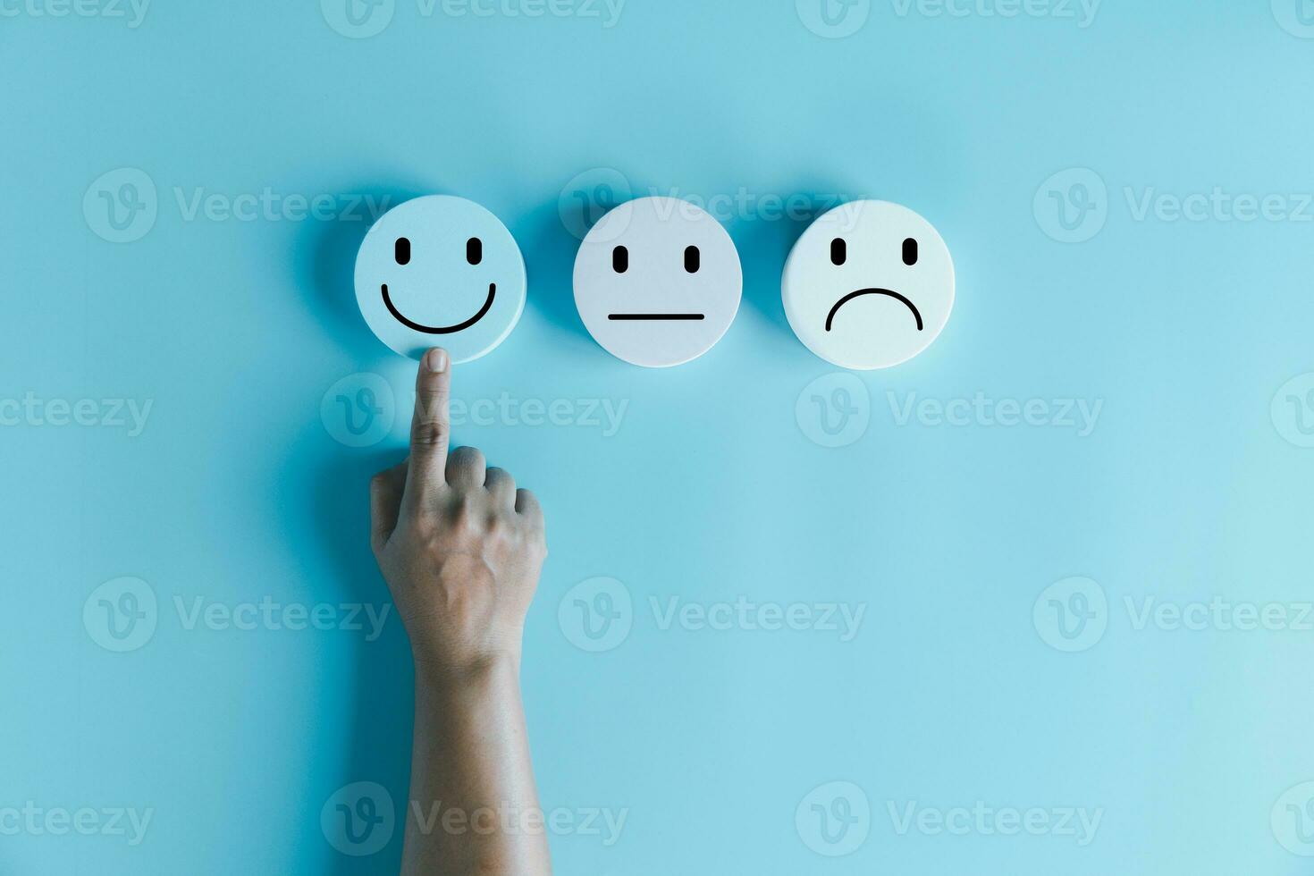 Woman hand touching happy face smile face icon on round blue object. Customer experience and service with satisfaction concept. positive thinking, mental health assessment, world mental health day. photo