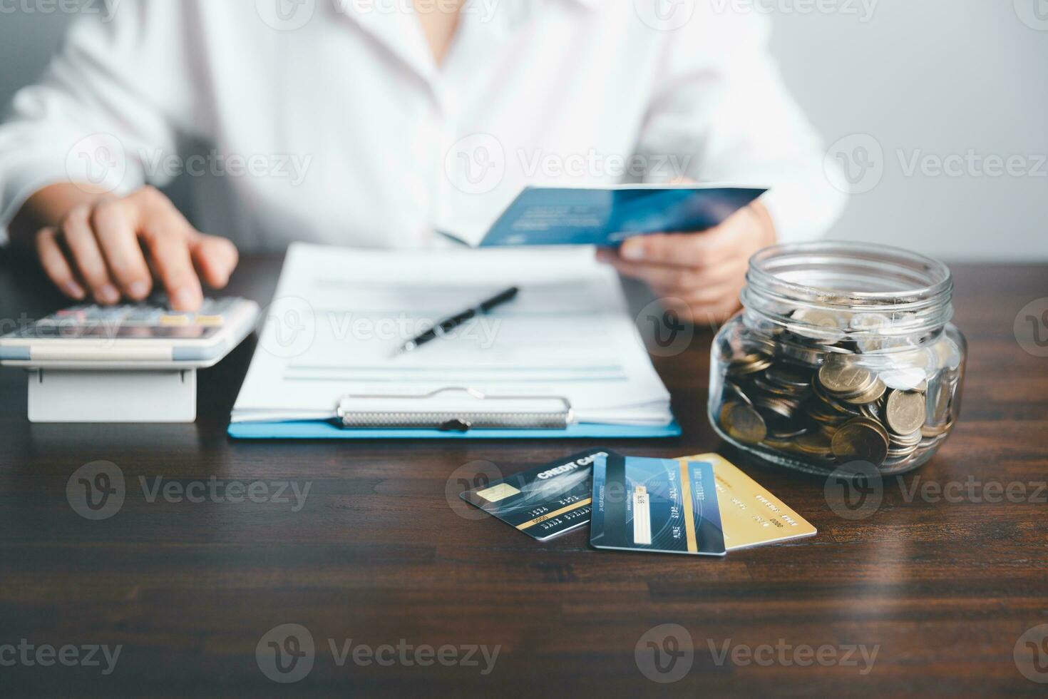 Business woman hands holding saving account passbook with calculator, account and saving concept. Asian woman checking bills, taxes, bank account balance and calculating credit card expenses. photo