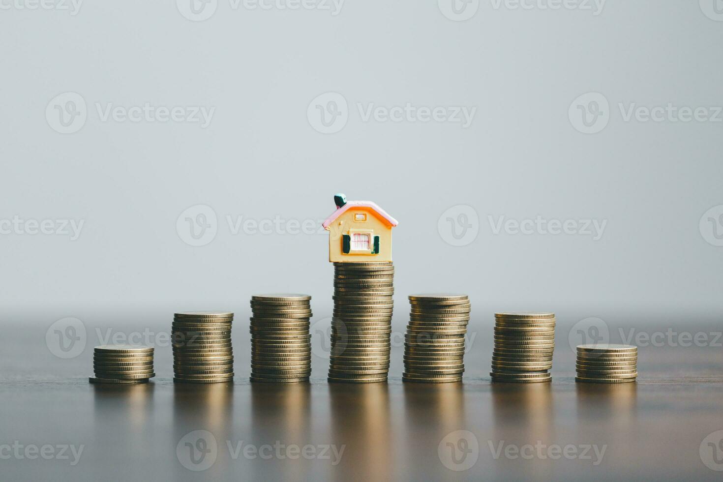 Coins stack with mini house on wooden table, home loan, Save money concept, Property investment, house loan, reverse mortgage, gold coins money stack growth, saving money coins stack future for home. photo