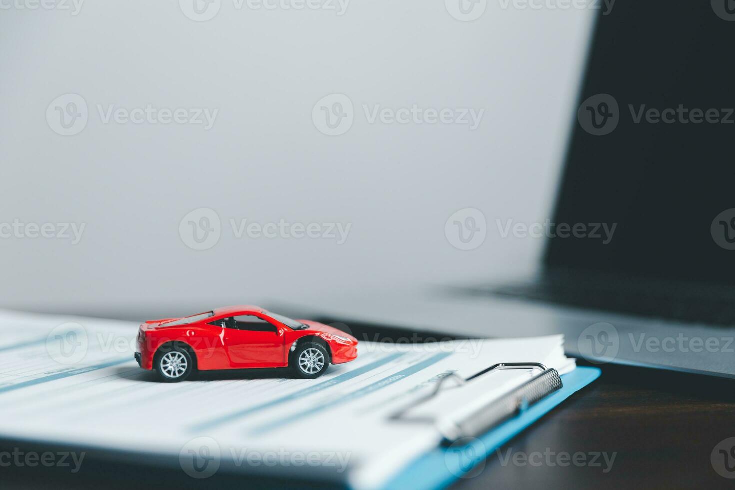 Business woman's hand protecting red toy car on desk. Planning to manage transportation finance costs. Concept of car insurance business, saving buy - sale with tax and loan for new car. photo