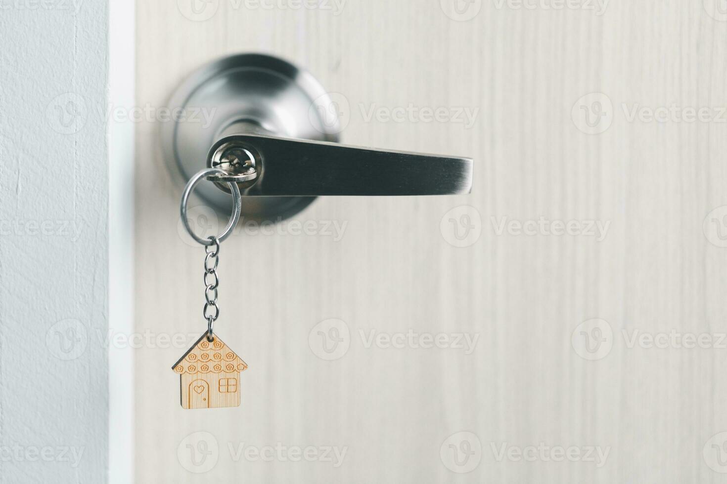 close up key on the door with morning light, personal loan concept. House model and key in house door. Real estate agent offer house, property insurance and security, affordable housing concepts. photo