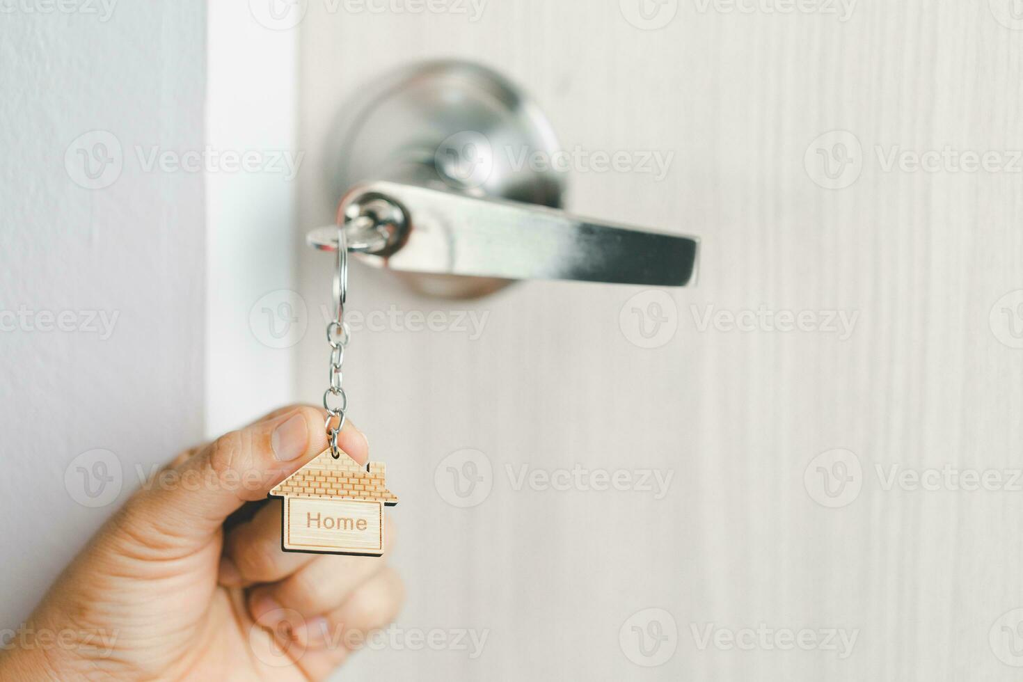 close up key on the door with morning light, personal loan concept. House model and key in house door. Real estate agent offer house, property insurance and security, affordable housing concepts. photo