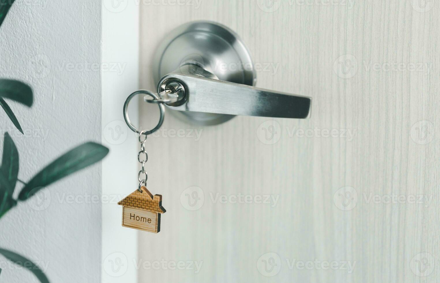 close up key on the door with morning light, personal loan concept. House model and key in house door. Real estate agent offer house, property insurance and security, affordable housing concepts. photo