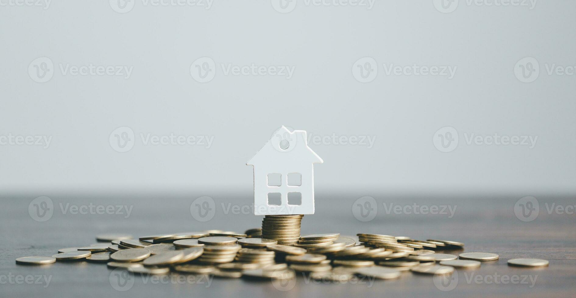 Coins stack with mini house on wooden table, home loan, Save money concept, Property investment, house loan, reverse mortgage, gold coins money stack growth, saving money coins stack future for home. photo