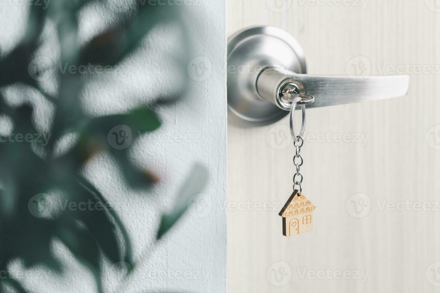 close up key on the door with morning light, personal loan concept. House model and key in house door. Real estate agent offer house, property insurance and security, affordable housing concepts. photo