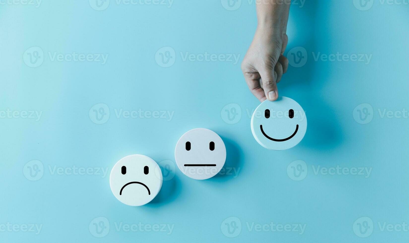 Woman hand holding happy face smile face icon on round blue object. Customer experience and service with satisfaction concept. positive thinking, mental health assessment, world mental health day. photo