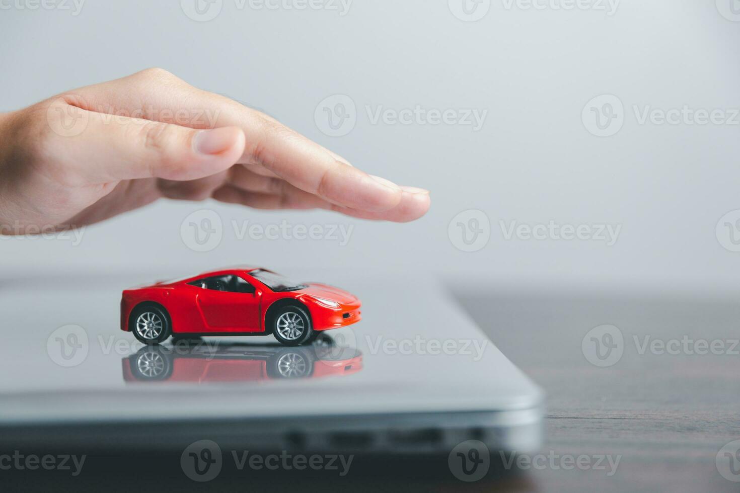 Business woman's hand protecting red toy car on desk. Planning to manage transportation finance costs. Concept of car insurance business, saving buy - sale with tax and loan for new car. photo